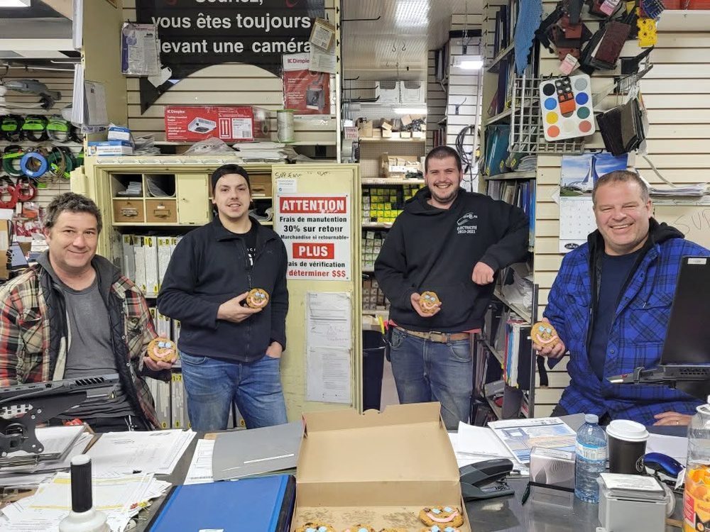 Quatre employés réunis au comptoir de vente pour « Le Vendredi sourire »